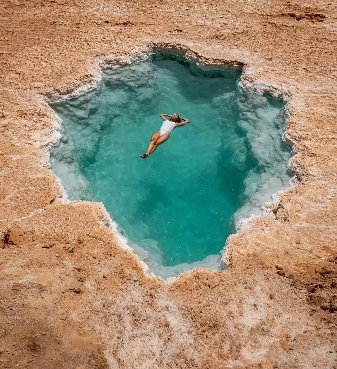 Traveller floating in a turquoise salt pool during a Siwa Oasis itinerary