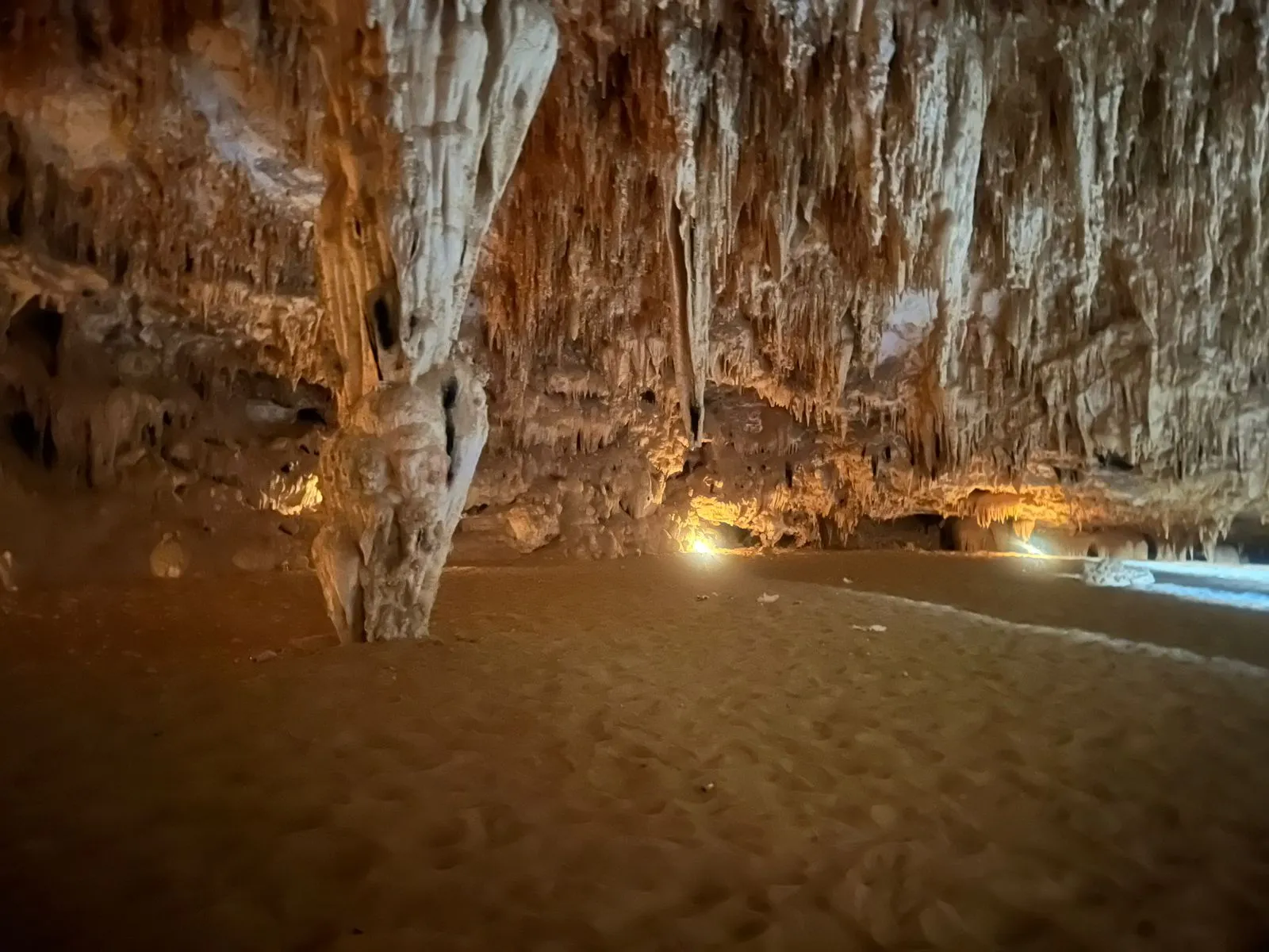 The stalactite chamber inside Djara Cave Egypt lit softly against the sandy cave floor