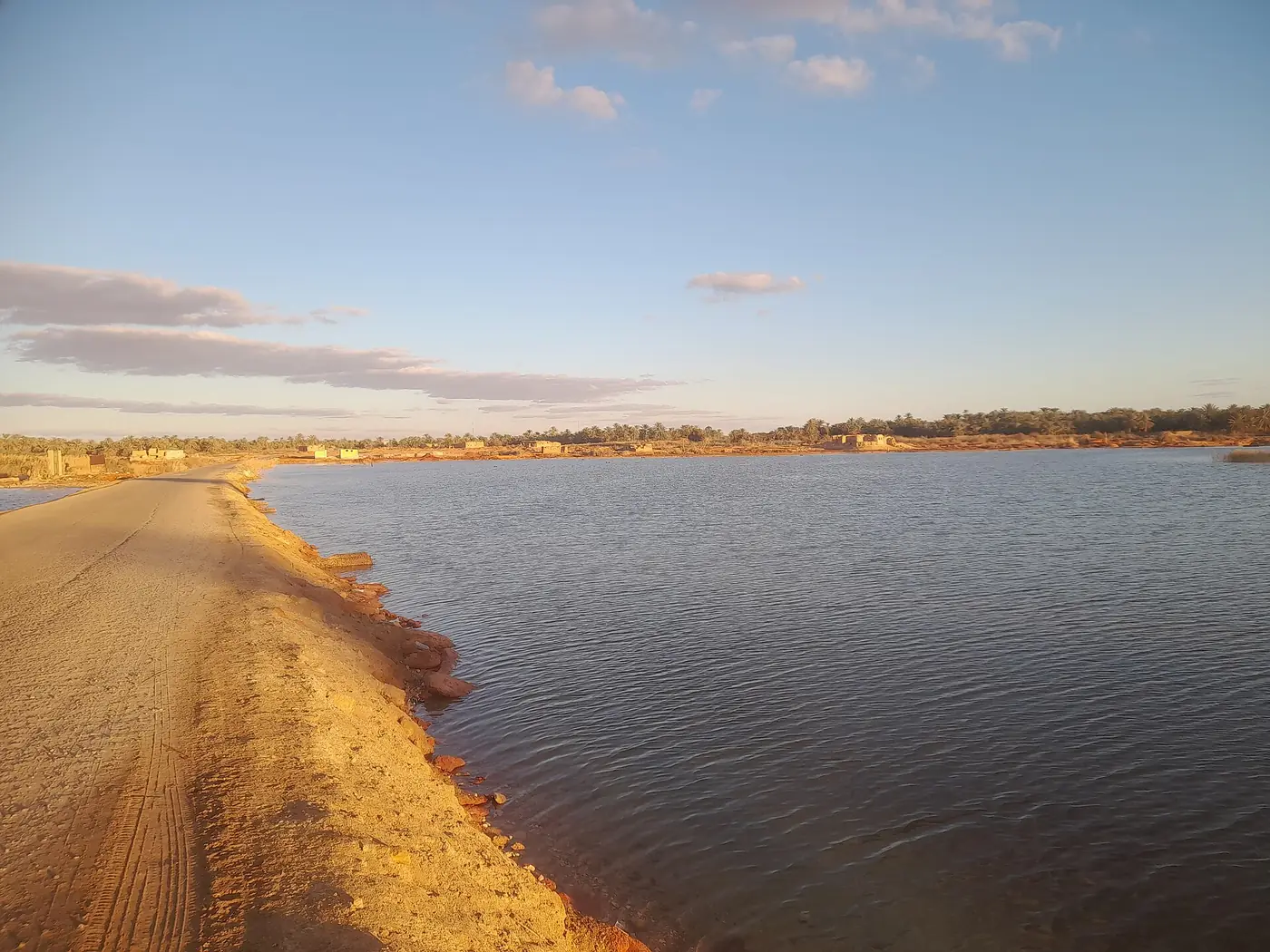 Causeway leading to Fatnas Island Siwa beside the calm waters of Lake Siwa