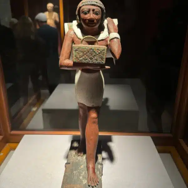 Ancient Egyptian offering bearer statue displayed in a museum gallery