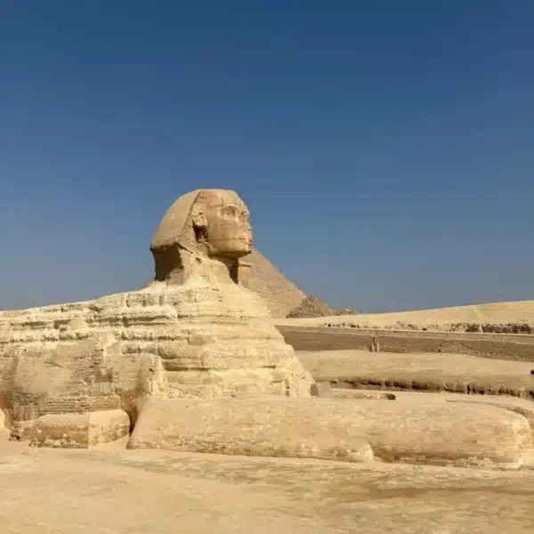 Great Sphinx side view with a pyramid in the distance