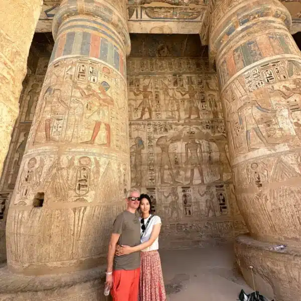 Travelers beside colorful decorated columns in a Luxor temple