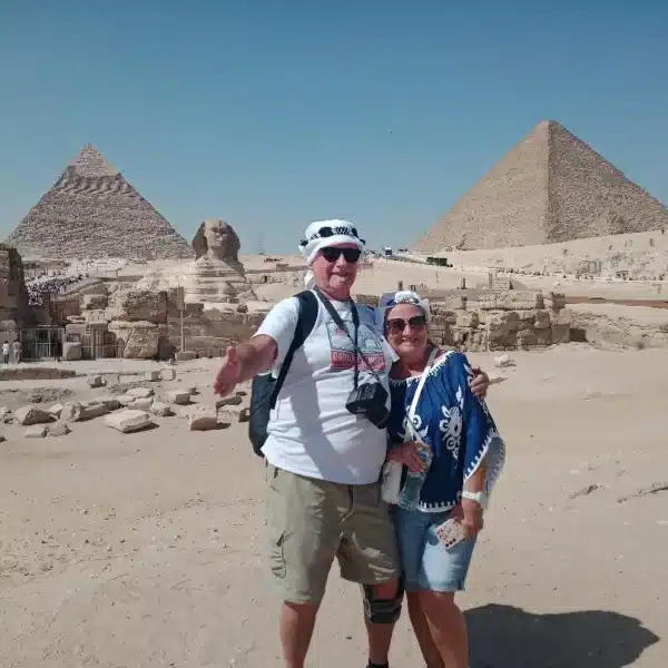 Two travelers with the Great Sphinx and Giza Pyramids behind them