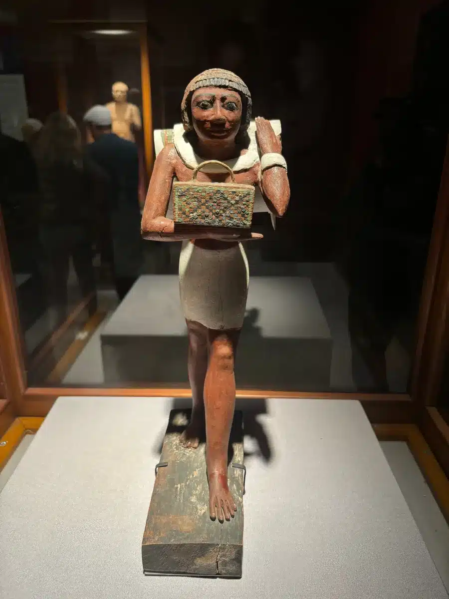Ancient Egyptian offering bearer statue displayed in a museum gallery
