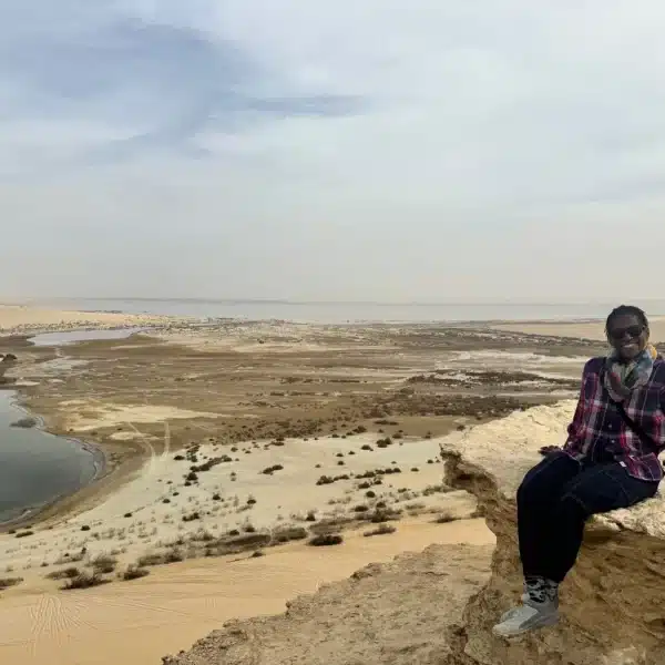 Traveler seated above Magic Lake and the Fayoum desert landscape