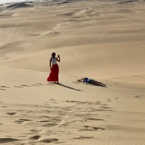 Traveler sandboarding on dunes in the Great Sand Sea near Siwa