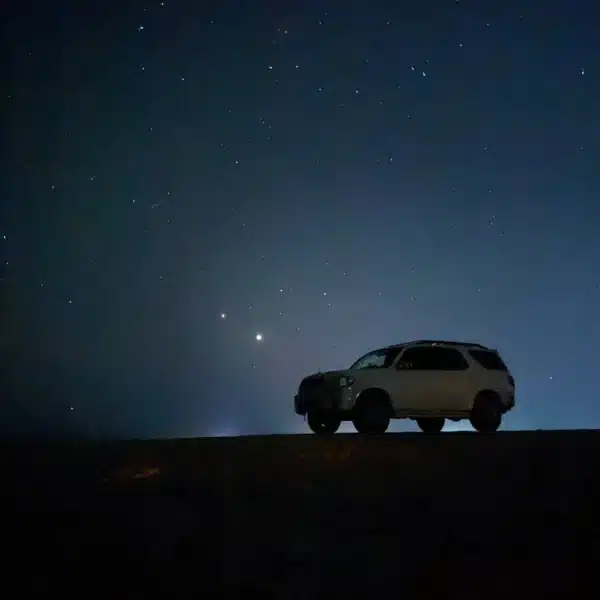 4x4 safari vehicle silhouetted beneath a starry sky in Siwa