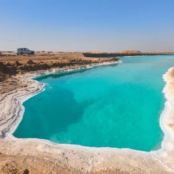 Turquoise salt lake surrounded by white salt banks in Siwa Oasis