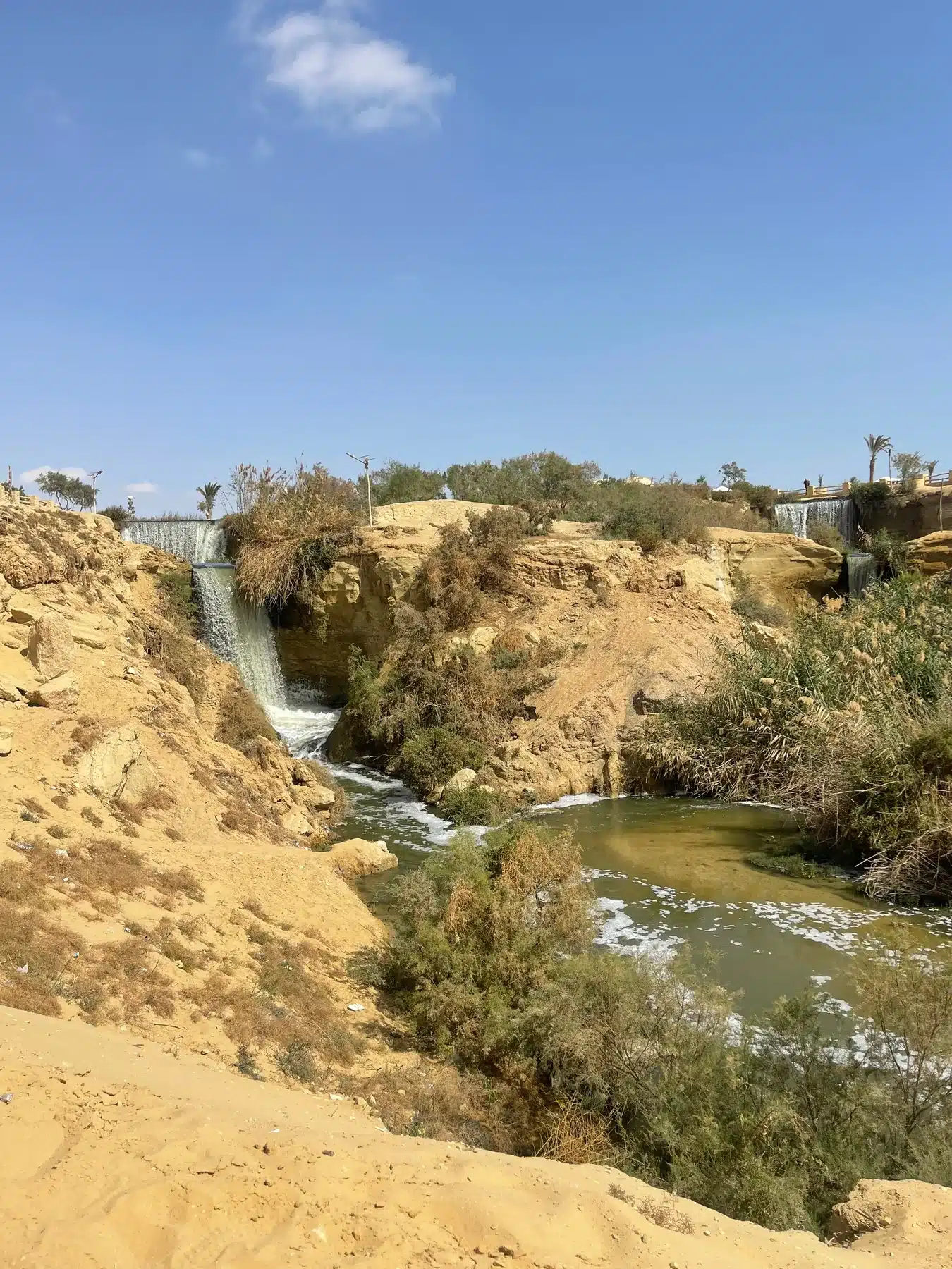Multiple waterfalls flowing through the Wadi El Rayan desert landscape
